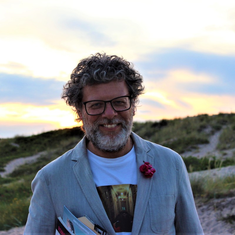 Mand med bøger i solnedgang på stranden
